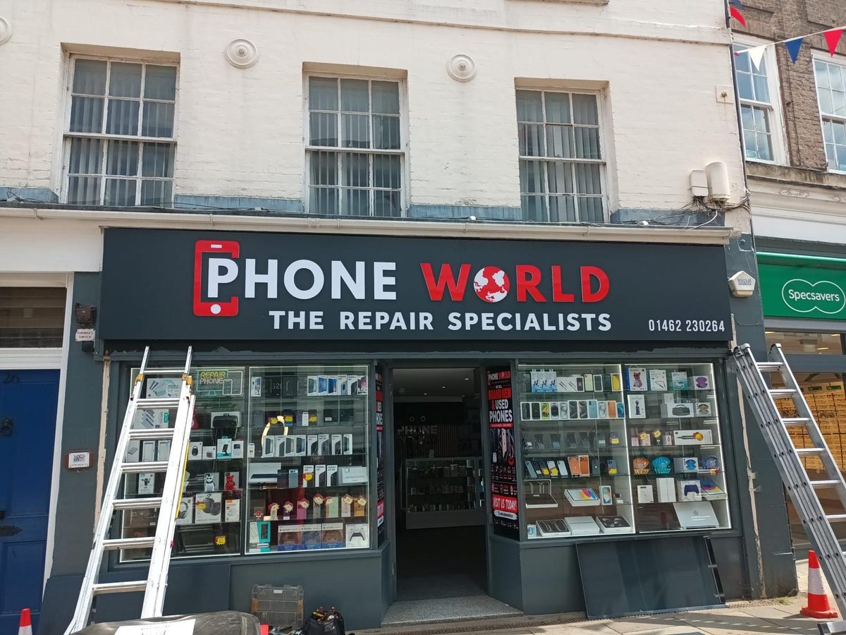 Fitters working from ladders on a Phone World shopfront sign