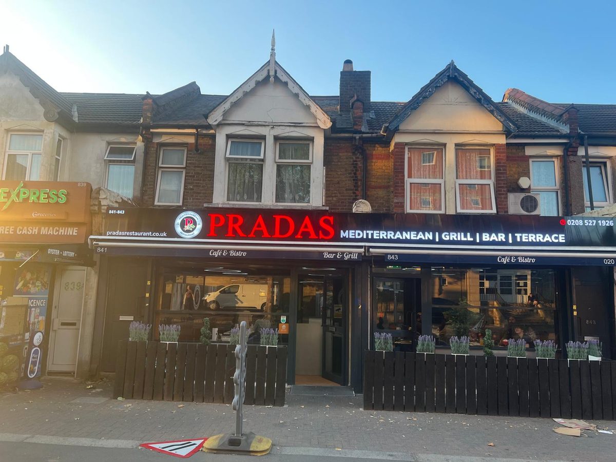 Wide shopfront with a red illuminated fascia sign on a London parade